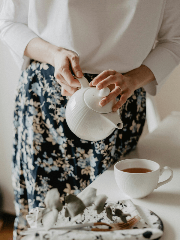 woman pouring oolong tea from teapot into teacup